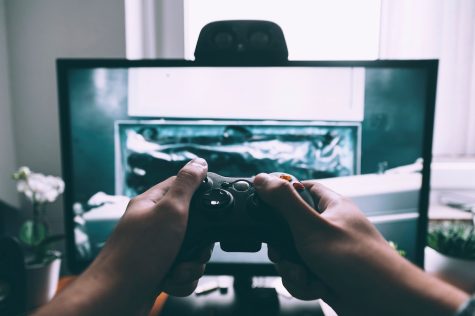 Person holding a game controller in front of a monitor